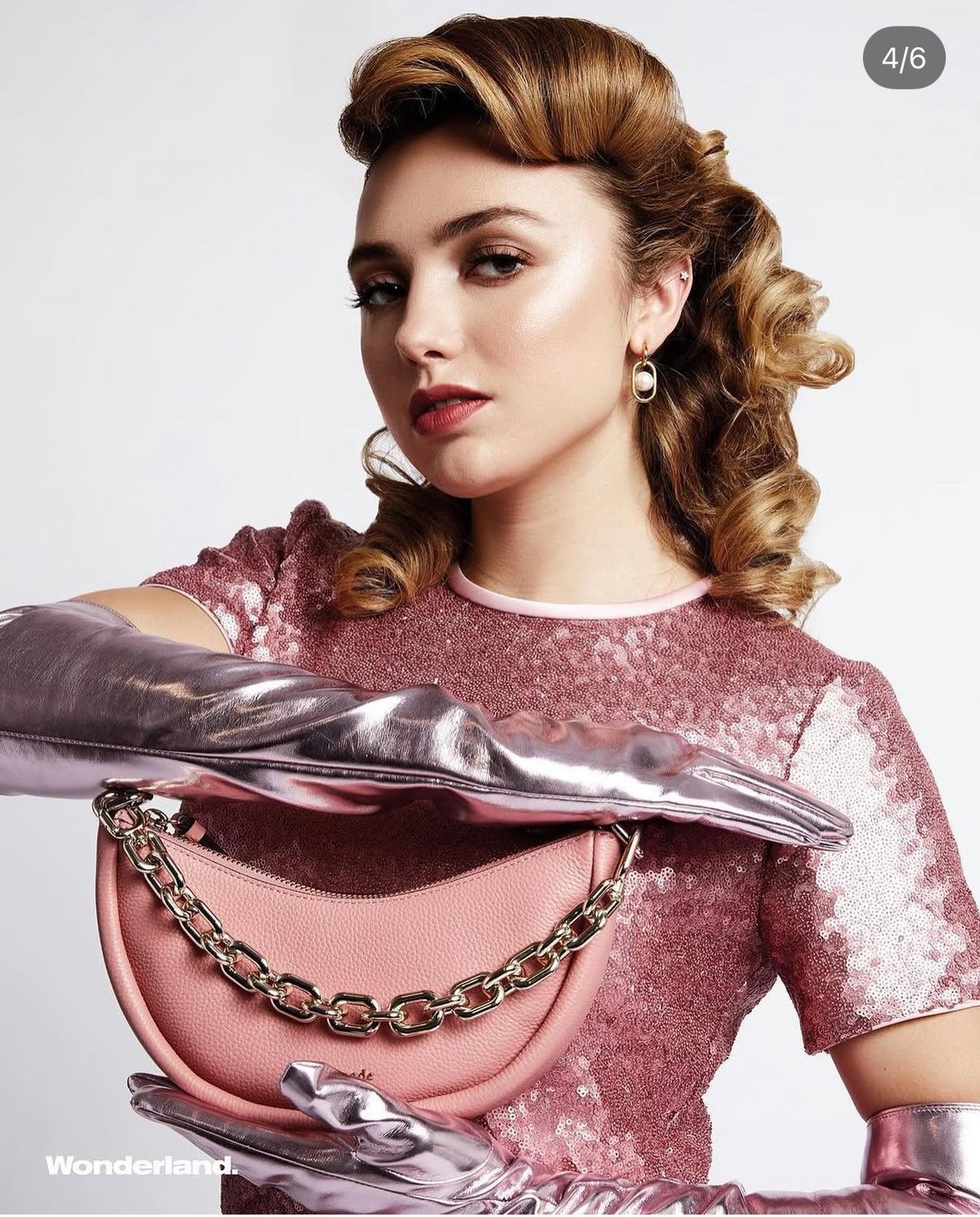 Peyton List of Cobra Kai in a metallic pink outfit with a pink handbag for Wonderland's Kate Spade collaboration